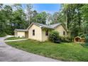 A yellow house on a lush green lawn, featuring an outbuilding to the side of the residence at 5357 Highway 81, Loganville, GA 30052