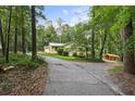 Scenic shot of a yellow home nestled among tall trees, showcasing a private driveway and natural landscape at 5357 Highway 81, Loganville, GA 30052