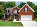 Beautiful brick home with a covered porch, lush landscaping, and attached two-car garage at 4613 Creek Forest Ct, Lilburn, GA 30047