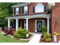 Close-up of the front porch featuring white columns, lush landscaping and a decorative front door at 4613 Creek Forest Ct, Lilburn, GA 30047