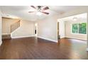Open-concept living room with hardwood floors, staircase, ceiling fan, and natural light at 5427 Highway 81, Loganville, GA 30052