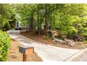 Scenic driveway winding through lush greenery and mature trees, leading to a modern home at 4052 Loch Highland Ne Pass, Roswell, GA 30075