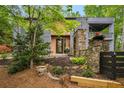 Inviting home exterior featuring stone accents, wood-style siding, and a stylish modern front entrance with black-trimmed door at 4052 Loch Highland Ne Pass, Roswell, GA 30075