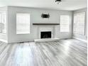 Bright living room featuring a modern fireplace, updated flooring, and ample natural light from large windows at 6945 Autumn Hills Dr, Cumming, GA 30028