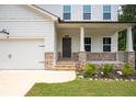 Inviting front porch with stone accents and manicured landscaping, adjacent to a two-car garage at 63 Brookstone E Park, Acworth, GA 30101