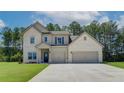 Lovely two-story home boasts a light brick exterior, covered porch, and a spacious two-car garage at 211 Linford Dr, Locust Grove, GA 30248
