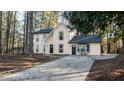 Two-story home with a concrete driveway, tan siding and black trim and windows surrounded by trees at 7156 Whitfield Dr, Riverdale, GA 30296