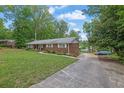 Brick home with a long driveway offering ample parking space surrounded by green lawn and mature trees at 1192 Pathfinder Rd, Marietta, GA 30066