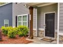 Home's front entrance with dark door, wood support beam, stone accents, landscaping, and visible house number at 209 Shelton Cir, Temple, GA 30179