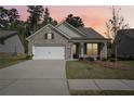 Charming single-story brick home with a two-car garage, well-kept lawn against the colors of the sunset at 3382 Long Creek Dr, Buford, GA 30519