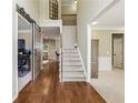 Hallway with wooden floors leads to an office, staircase, and living room with a sliding barn door at 6720 Wolford Ct, Johns Creek, GA 30097