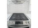Close-up of stainless steel gas stove with modern vent hood and white tile backsplash at 1740 Langston Sw Ave, Atlanta, GA 30310
