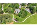 Expansive home with a pool, circular driveway, and lush landscaping, surrounded by mature trees and a golf cart path at 5045 Harrington Rd, Johns Creek, GA 30022