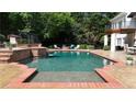 A refreshing in-ground pool with brick accents and a small waterfall feature is surrounded by patio furniture at 5045 Harrington Rd, Johns Creek, GA 30022
