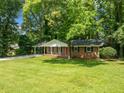Well-maintained one-story home featuring a brick facade, inviting front porch, and lush green lawn with mature trees at 2683 Stardust Trl, Decatur, GA 30034