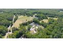 Aerial view of a large property with multiple buildings and a horse pasture surrounded by trees at 604 Trinity Church Rd, Canton, GA 30115