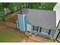 Aerial view of a blue house with a gray roof, landscaping, and a fenced backyard at 6597 Ivy Log Dr, Austell, GA 30168