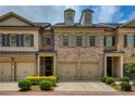 Charming brick townhome with a two-car garage, complemented by manicured landscaping and classic architectural details at 385 Windy Pines Trl, Roswell, GA 30075