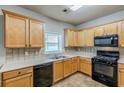 Functional kitchen with wooden cabinetry, black appliances, tile backsplash, and a bright window at 8826 Lakecrest Way, Union City, GA 30291