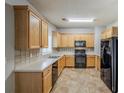 Well-lit kitchen featuring wooden cabinets, black appliances, and neutral countertops at 8826 Lakecrest Way, Union City, GA 30291