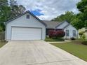 Inviting single-story home featuring an attached garage and beautifully landscaped front yard at 5298 Autumn Run Dr, Powder Springs, GA 30127
