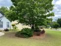 Home's lovely landscaped front yard with mature tree offering nice shade and curb appeal at 5298 Autumn Run Dr, Powder Springs, GA 30127