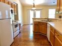 Well-lit kitchen with white appliances, light wood cabinets, and hardwood flooring, flowing into the dining area at 5298 Autumn Run Dr, Powder Springs, GA 30127