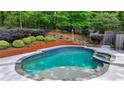 Backyard with a beautiful in-ground pool and spa, surrounded by lush greenery at 5335 Bannergate Dr, Johns Creek, GA 30022