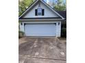 Attached two-car garage with a white paneled door, exterior lighting, and a concrete driveway at 5028 Highway 81, Mcdonough, GA 30252