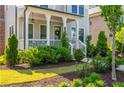 Attractive landscaping leading to a cozy covered porch with hanging pendant lights at 750 Tannery Cmn, Alpharetta, GA 30009