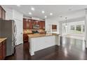 Well-lit kitchen featuring a large island with granite countertops, stainless steel appliances, and dark hardwood floors at 3700 Terrasol Sw Trl, Lilburn, GA 30047