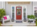 Welcoming front entrance with a red door, sidelights, bench, and decorative lanterns and planters at 1700 Prospect Way, Conyers, GA 30094