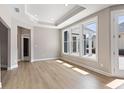Sun-filled living room featuring hardwood floors, tray ceiling, and large windows at 313 Sassafras Way, Holly Springs, GA 30115