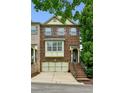 Inviting brick townhome featuring a two-car garage and a quaint entrance staircase leading to the front door at 2143 Yancey Ne Ln, Atlanta, GA 30319