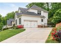 Rear view of a bright home with a two-car garage and blooming flowerbeds at 690 Sienna Dr, Cumming, GA 30040