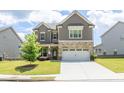 Inviting two-story home featuring stone accents, a manicured lawn, and a two-car garage under a partly cloudy sky at 3477 Ivy Birch Way, Buford, GA 30519
