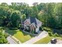 Aerial view of two-story brick home featuring a beautifully landscaped front yard, basketball court and driveway at 3705 Rolling Creek Dr, Buford, GA 30519