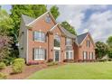 Side angle of the two-story brick home with manicured lawn and mature trees at 352 Hickory Haven Ter, Suwanee, GA 30024