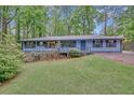 Charming single-story home featuring blue siding, a welcoming front porch, and a lush, wooded lot at 4856 Rock Haven Dr, Lilburn, GA 30047