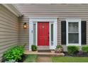 Close up on a red front door with sidelights and decorative molding, flanked by potted plants at 2640 Garland Way, Duluth, GA 30096