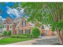 Brick house featuring professionally landscaped front yard and mature trees under a sunny sky at 9810 Foxworth Dr, Alpharetta, GA 30022