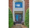 Elegant front entrance with custom iron doors, stone steps, and manicured greenery at 9810 Foxworth Dr, Alpharetta, GA 30022