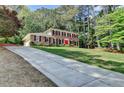 Charming brick home with a long driveway surrounded by lush greenery and mature trees at 1450 Holly Bank Cir, Atlanta, GA 30338