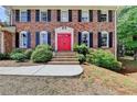 Close-up of brick home's front entrance with vibrant red double doors and classic black shutters at 1450 Holly Bank Cir, Atlanta, GA 30338