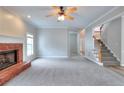 Open living space featuring a brick fireplace, neutral carpet, and staircase at 931 Bonaventure Way, Lawrenceville, GA 30044