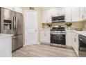 Modern kitchen with stainless steel appliances, white cabinets, quartz countertops, and wood-look floors at 136 Peachtree Memorial Nw Dr # Va2, Atlanta, GA 30309