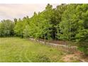 A view of a large grass-filled yard and a long, wooden fence bordering a property line at 7 Perkins Mountain Rd, Kingston, GA 30145