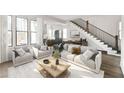 Bright living room featuring a modern sofa, stylish decor, staircase, and an open floor plan at 11530 Serenbe Ln, Chattahoochee Hills, GA 30268