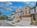 Beautiful townhome exterior with stone and brick accents, a trellised garage and blue sky at 116 Via Roma, Woodstock, GA 30188