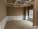 Neutral-toned room featuring a coffered ceiling, classic wainscoting, and bright natural light from a window at 3648 Lake Estates Way, Atlanta, GA 30349